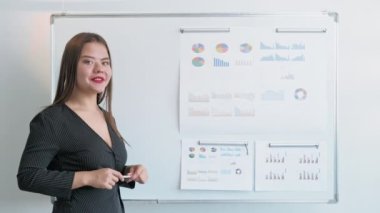 Çevrimiçi istatistik raporu. Sanal konferans. Uzaklık veri analizi. Kendine güvenen iş kadını çizelgeleri tahtaya koyuyor. Uzun video çekimi.