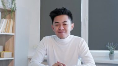 Çevrimiçi toplantı. Uzaktan görüşme. Mesafe konferansı. Neşeli, meraklı erkek çalışan el sallayarak modern ofis içini dinliyor. Uzun video çekimi.