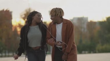 Romantik bir randevu. Müziğin tadını çıkarıyorum. Memnun oldum. Mutlu siyah kadın ve erkek kulaklıklarını paylaşıyor. Akıllı telefondan favori şarkılarını dinliyorlar. Yavaş çekimde dans ediyorlar..