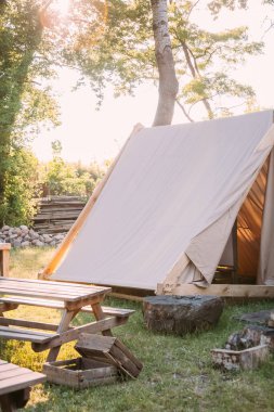 Kırsal kamp. Dinlenme bölgesi. Yakın doğa. Gün ışığı bahçesinde piknik masalı çadır ve dışarıda tahta kutular..