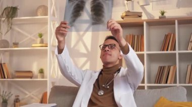 Akciğer kontrolü. Teşhis radyolojisi. Akciğer enfeksiyonu. Düşünceli erkek doktor modern iç mekanda göğüs röntgeni üzerinde çalışıyor..