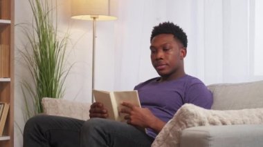 Tembel hafta sonu. Ev istirahatı. Pazar yorgunluğu. Akıllıca bir eğlence. Modern oturma odasındaki koltukta kitap okuyup uyuyakalan rahat adam..