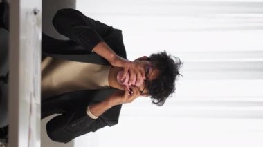 Dikey video. Yorgun rapor. Çaresiz adam. Yorgun iş. Değişken gözlükleri olan yorgun adam saçlarını kirletiyor. Kahve fincanının içini içiyor..