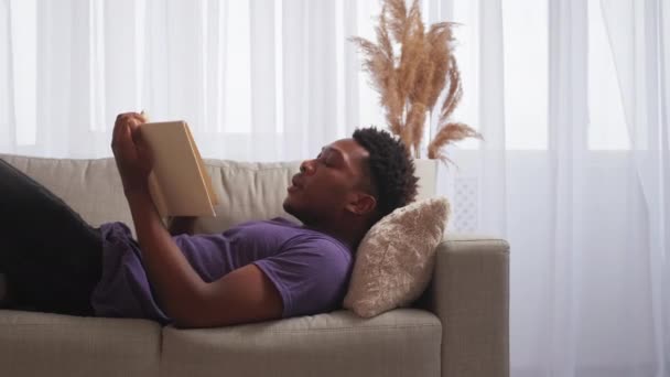 阅读休闲 周末休息 周日的文学 一个放轻松的家伙 开著书躺在家里舒适的沙发上 有空余的空间 — 图库视频影像