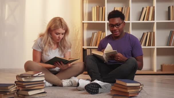 学生的生活方式在家学习 聪明的休闲 在客厅里 一对聪明的 多姿多彩的情侣盘腿坐在地板上 享受看书的乐趣 — 图库视频影像
