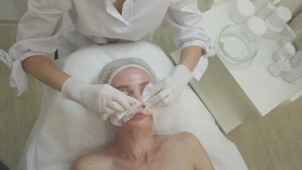 美容室 顔の治療 スキンケア療法 軽い室内での手続きの前に 中年女性の顔の皮膚を栄養専門の美容師 — ストック動画