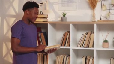 Okuma hobisi. Ev kütüphanesi. Edebiyat koleksiyonu. Kitaplıkta sayfaları çevirmekten hoşlanan, açık kitaplı, meraklı, memnun bir adam..