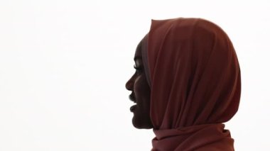 Doğulu bir kadın. İlham verici bir konuşma. Profil portresi. Tesettürlü güzel bayan, beyaz arka planda biriyle konuşuyor..