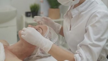 Güzellik salonu. Kadın bakımı. Yenilenme işlemi. Tanımlanamayan kozmetik uzmanı cilde jel kozmetik uyguluyor..