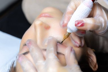 Elinde kalıcı bir makyaj makinesi tutan bir dövme sanatçısının elleri.