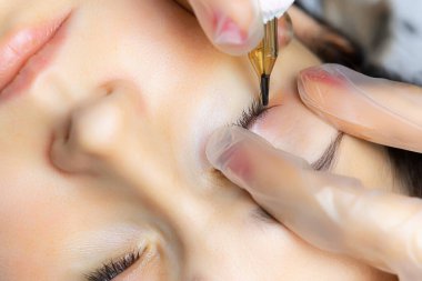 Dövmeci modelin göz kapaklarını gerer ve dövmeyi yapar.