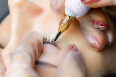 Dövmeci modelin göz kapaklarını gerer ve dövmeyi yapar.