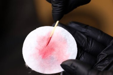 Usta, müşteriye gölgeyi göstermek için dövme pigmentini pamuk beyazı bir süngere sürer.