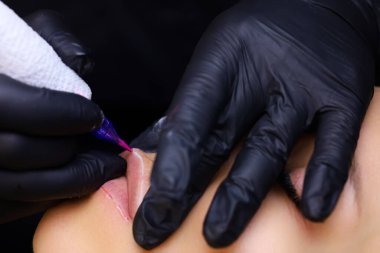 Dövme makinesinin burnuna ve iğnesine yakın çekim dudakların çevresi boyunca dövme yapar.