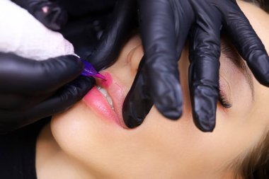 Usta çalışmalar modelin üst dudağının kalıcı makyajını yapar.