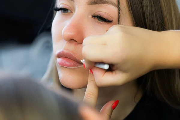 applying the contour on the lips with a white pencil before the procedure of permanent lip makeup
