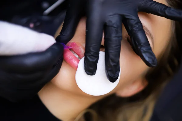 예술가는 스펀지를 의뢰인의 입술에 색소가 퍼지지 문신을 — 스톡 사진