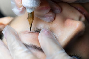 Dövme makinesiyle kirpiklerin yakın plan dövmesi.