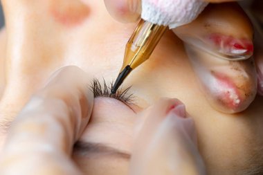 Dövmeci modelin göz kapaklarını gerer ve dövmeyi yapar.