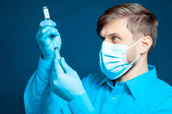 青い制服を着た医者が注射器にワクチンをダイヤルします — ストック写真