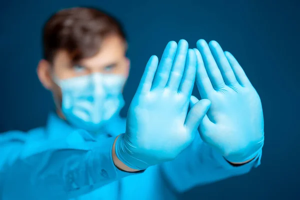 青い制服の医者は彼の手のひらの前に手を置き 記号を示しています — ストック写真