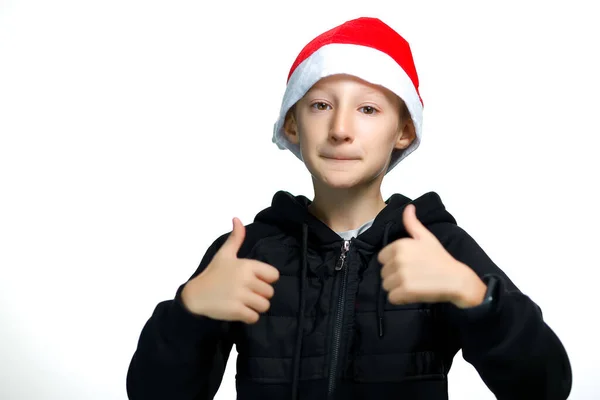 戴圣诞老人红帽子的男孩竖起大拇指 — 图库照片