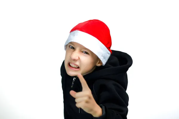 一个戴着红帽子的男孩露出食指 并威胁说要把他的牙齿露出来 — 图库照片