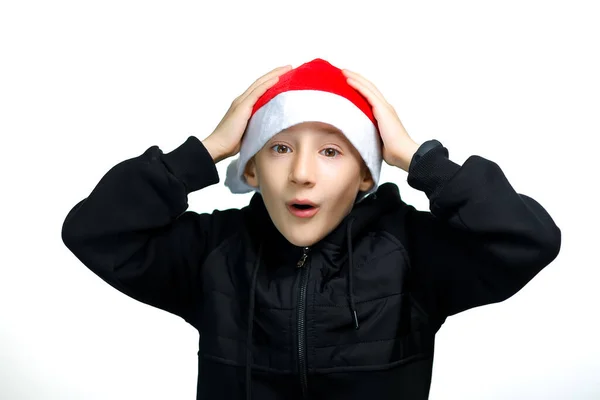戴着红色圣诞老人帽的男孩紧紧抓住头 吓得张开嘴 — 图库照片