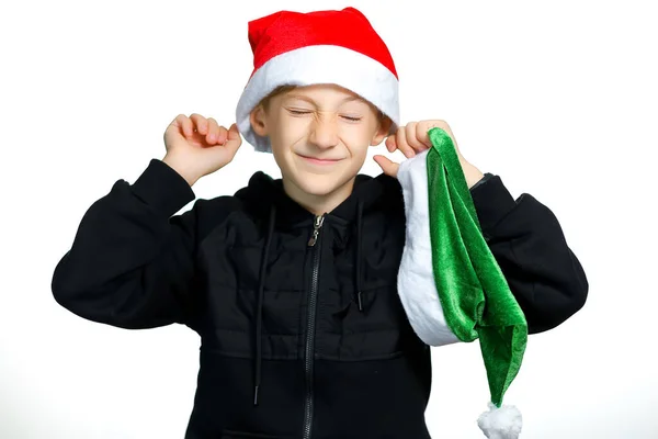 Pojke Står Vit Bakgrund Sätter Röd Santa Hatt Huvudet — Stockfoto