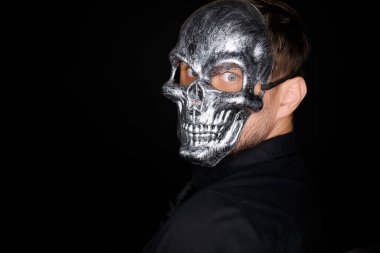 İskelet maskeli bir adamın portresi kameraya döner.