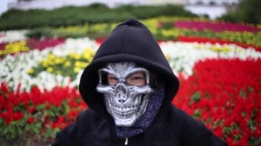 İskelet maskeli ve siyah başlıklı bir çocuk korkutur.