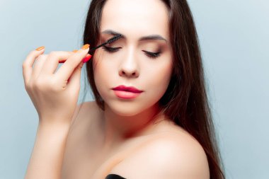 Güzel, narin makyajlı esmer model gözlerini kapadı ve kaşlarındaki kılları fırçayla taradı.