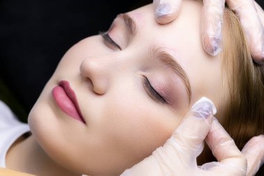 Üstat, mankenin yüzündeki pamuk çubuğuyla fazla kaş şeklini siliyor.