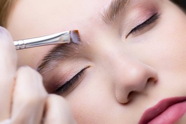 Ustanın kaplamalı kompozisyonları fırçayla uyguladığı modelin kaşlarının yakın çekimi