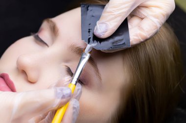 Usta, paketin üzerindeki kaş kaplamaları için kompozisyonu sıkıştırır, fırçayla.