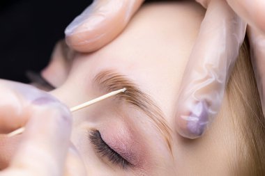 Usta, modelin kaşlarının üzerine tahta bir sopayla kaplama kompozisyonları dağıtır.