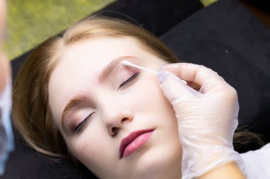 Üstat, kaş çevresindeki fazla katmanlı bileşimi pamuklu çubukla temizler.