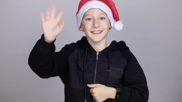 Veselý chlapec v červeném klobouku Santa Claus, dívá se do kamery — Stock video