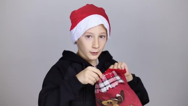 Chlapec v klobouku Santa Claus vypadá v dárkové tašce a dostane vztek — Stock video