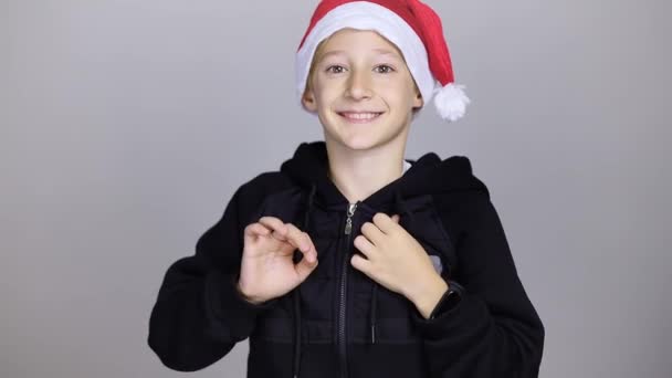 Een Vrolijke Jongen Een Kerstman Hoed Springt Vrolijk Geeft Een — Stockvideo