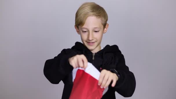 Een Vrolijke Jongen Een Kerstman Hoed Een Grijze Achtergrond — Stockvideo