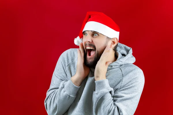 Kırmızı Noel Arka Planında Noel Baba Şapkalı Bir Adam Ayakta — Stok fotoğraf
