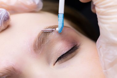 Kaş temizleme prosedüründen sonra kaş kıllarını seren usta, kaşları fırçayla tarıyor.