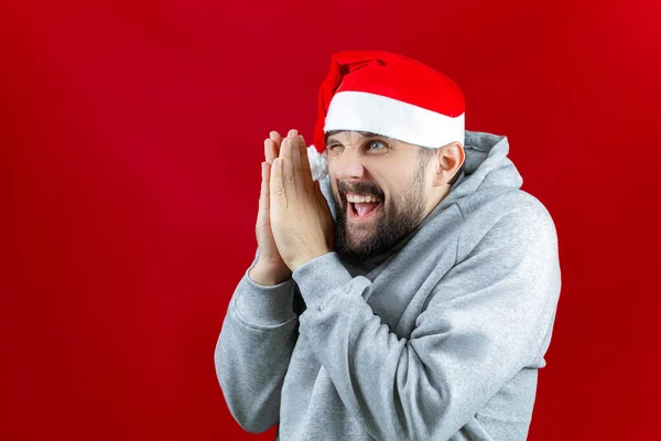 Man Santa Claus Hat Red Christmas Background Rubs His Hands — Stock Photo, Image