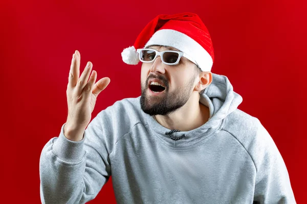 Man Red Santa Claus Hat Red Christmas Background Puts His — Stock Photo, Image