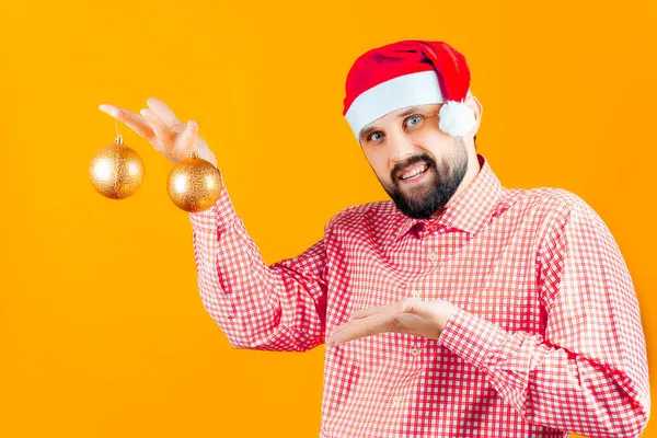 Ein Mann Mit Weihnachtsmütze Vom Weihnachtsmann Hält Weihnachtsspielzeug Goldene Kugeln — Stockfoto