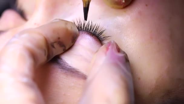 Protáhne oční víčka dvěma prsty a přiloží k řasám tetování — Stock video