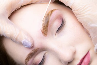 Kaş hatlarının, prosedür katmanından ve kaşların renklendirilmesinden sonra pamuk çubukla yakın çekim hizalanması.