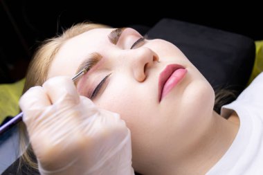 Modelin kaşlarına yakın çekim. Üstat, kaş kıllarını bileşiklerle renklendirmek için kalın bir boya tabakası uyguluyor.