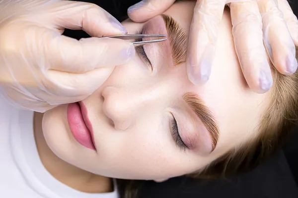 correction of the model\'s eyebrows with tweezers and removal of excess hairs from the contour of the eyebrows after the lamination and coloring procedure